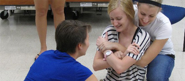 two female students demonstrate lifting a female patient