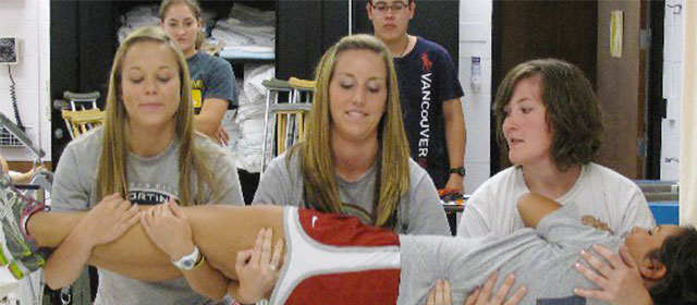 three female students demonstrate moving a female patient